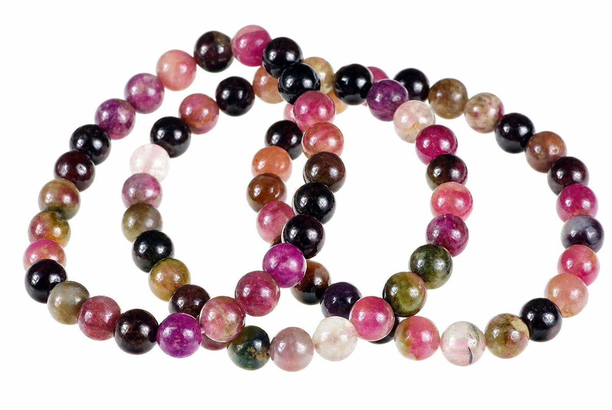 A multi-color tourmaline bracelet with round beads in pink, black, green, and brown arranged on a white background.