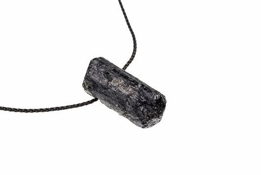 A black, raw tourmaline crystal pendant on a dark cord against a white background.