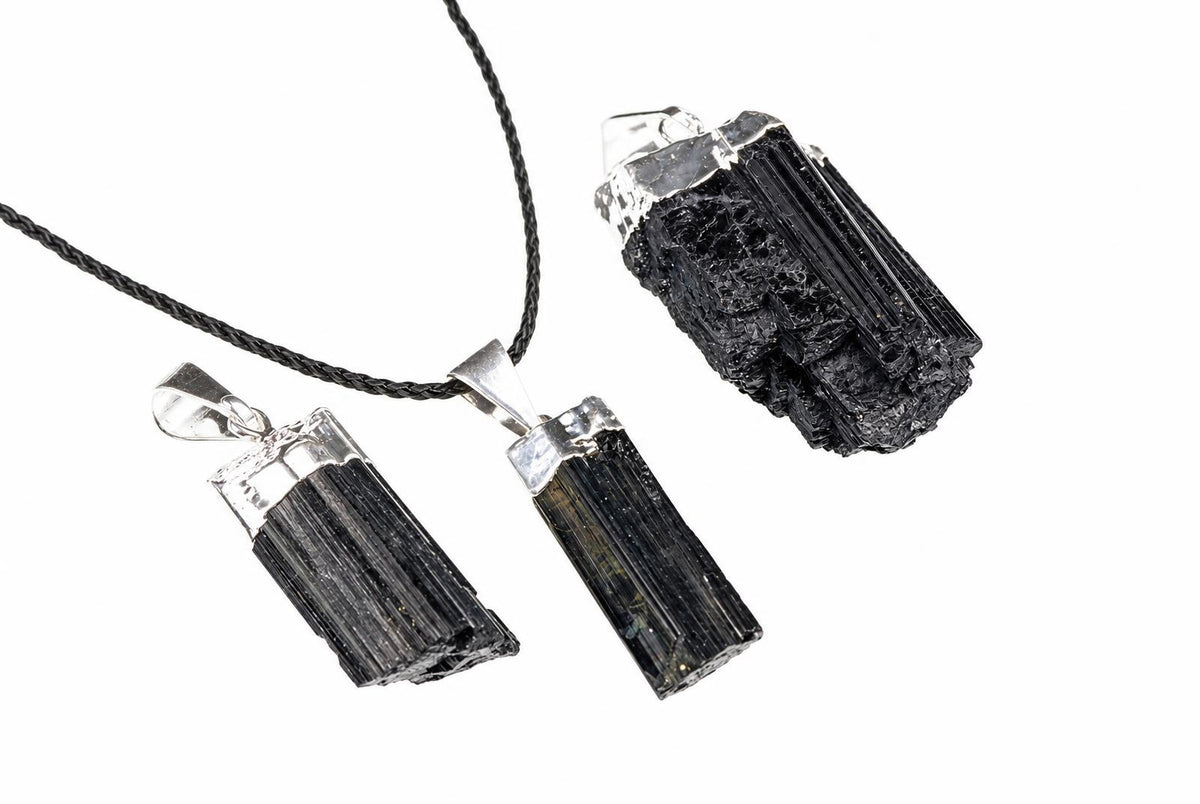 Three black tourmaline crystal pendants with silver-toned settings on a dark cord, displayed against a white background.