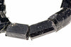 A bracelet made of raw, dark black tourmaline schorl crystals with a rough, faceted surface on a white background.