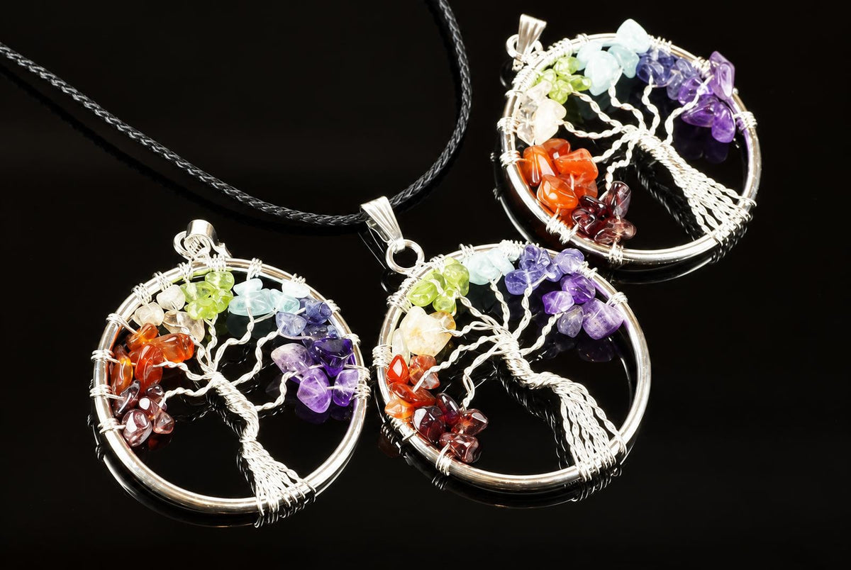 Circular pendants feature silver toned wire trees with colourful stones arranged along their branches, lying with a black cord on a dark surface.