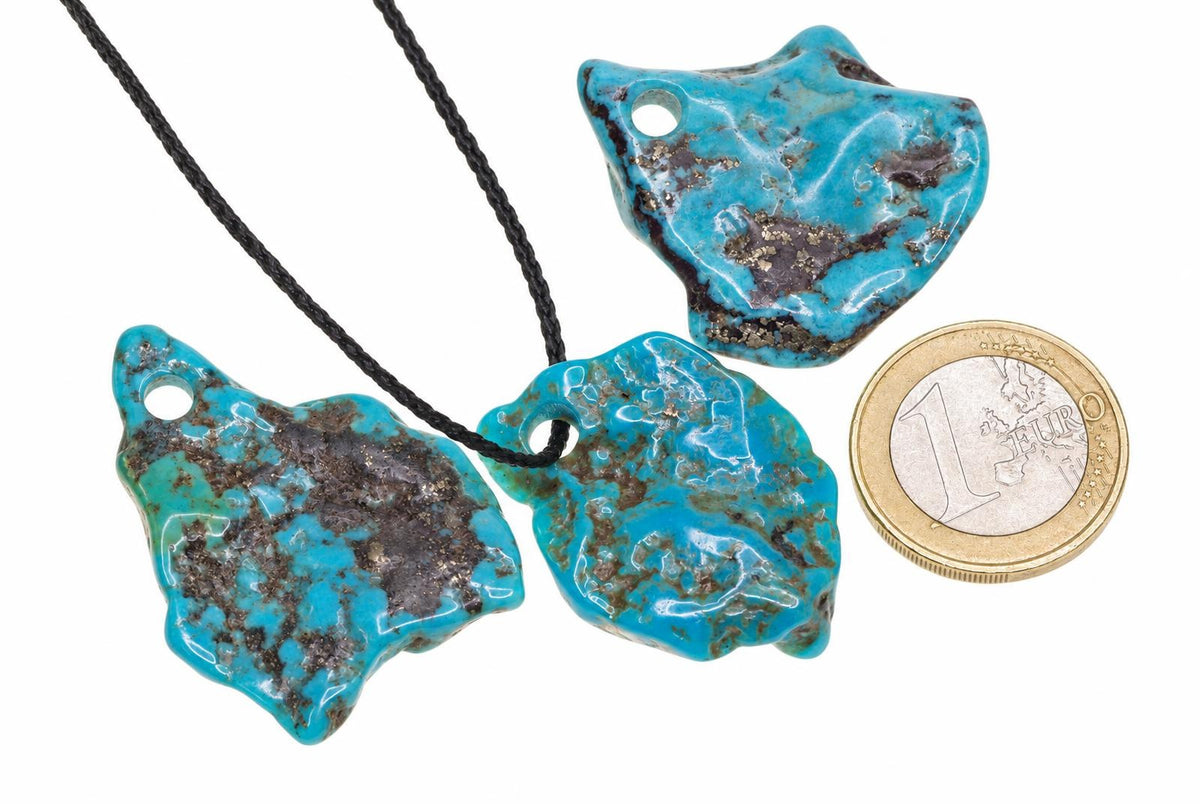 Three turquoise pendants with dark matrix patterns on a white surface, one attached to a black cord, next to a one euro coin.