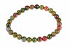A bracelet of round beads in red, green and dark tones on a white background.