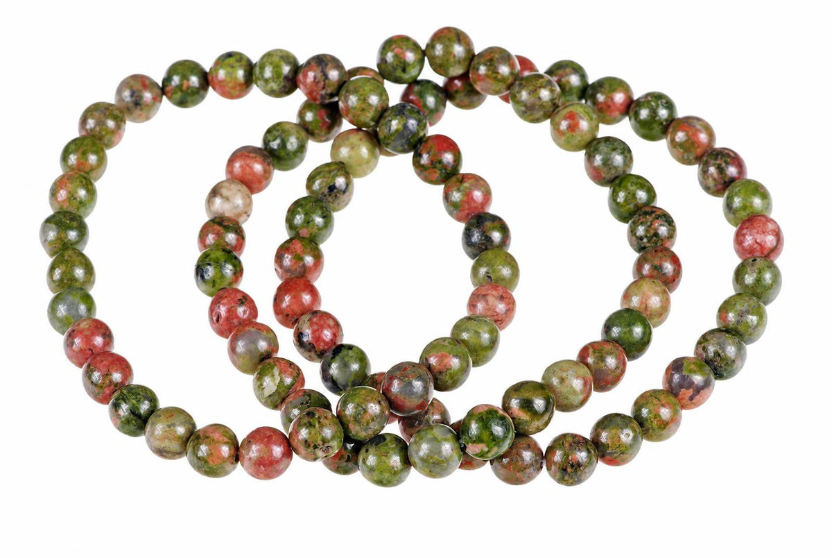 A bracelet of round beads with green, red and black speckled patterns on a white background.