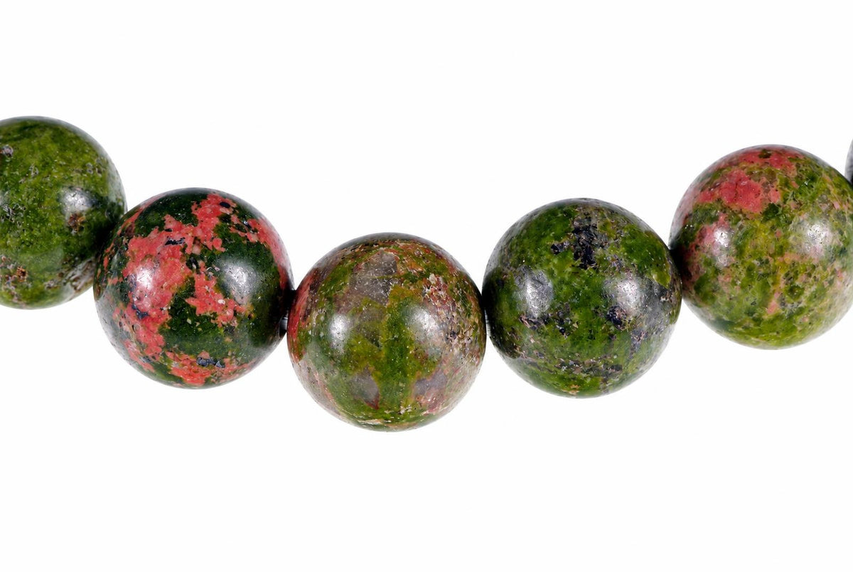A row of round beads with green and red speckled patterns on a white background.