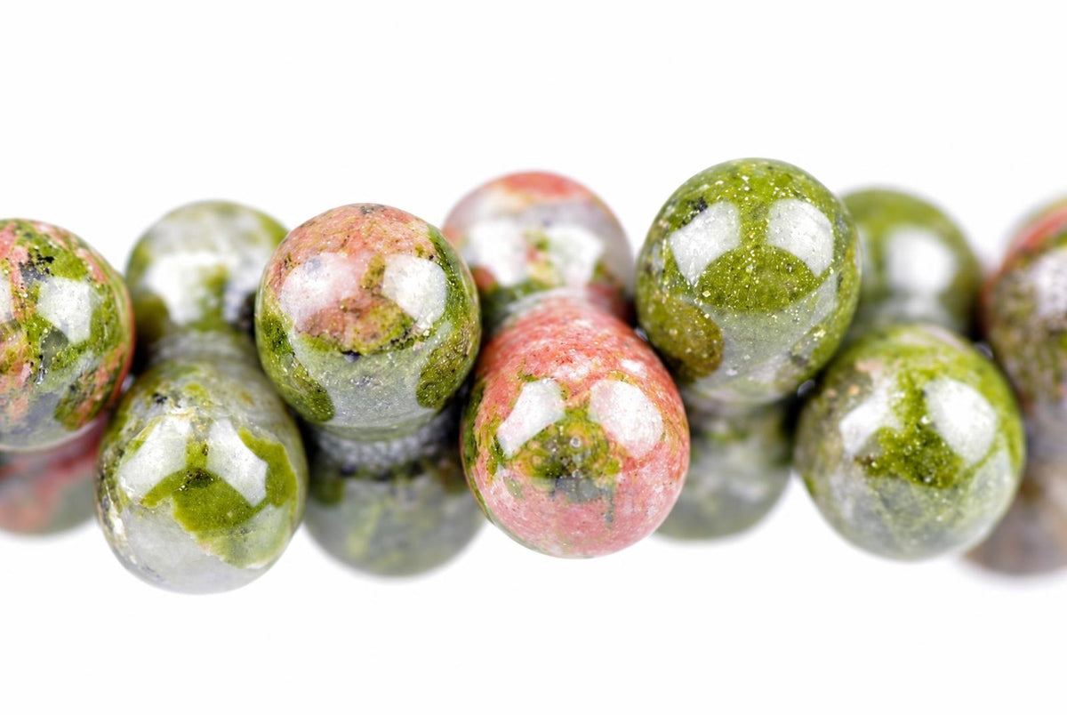 A row of round beads with pink, green and white patterns on a pale surface.
