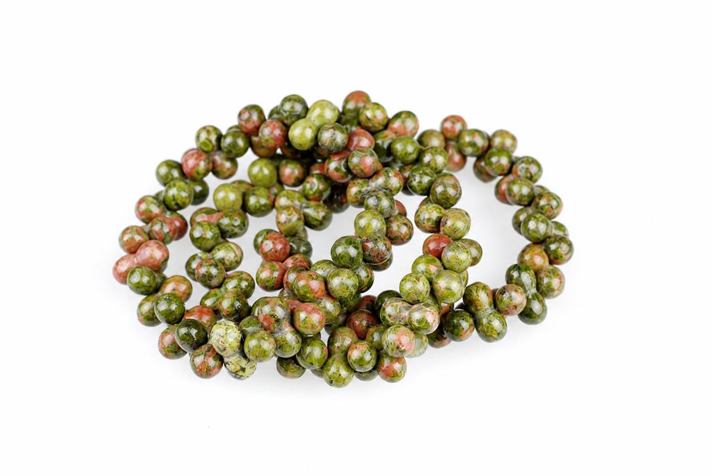 A coil of round beads with green and red speckled patterns on a white surface.