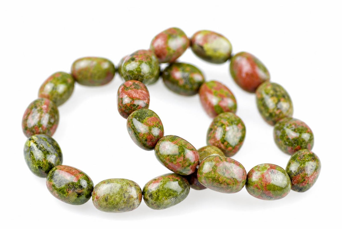 A bracelet of oval beads with green, red and white speckled patterns on a pale surface.