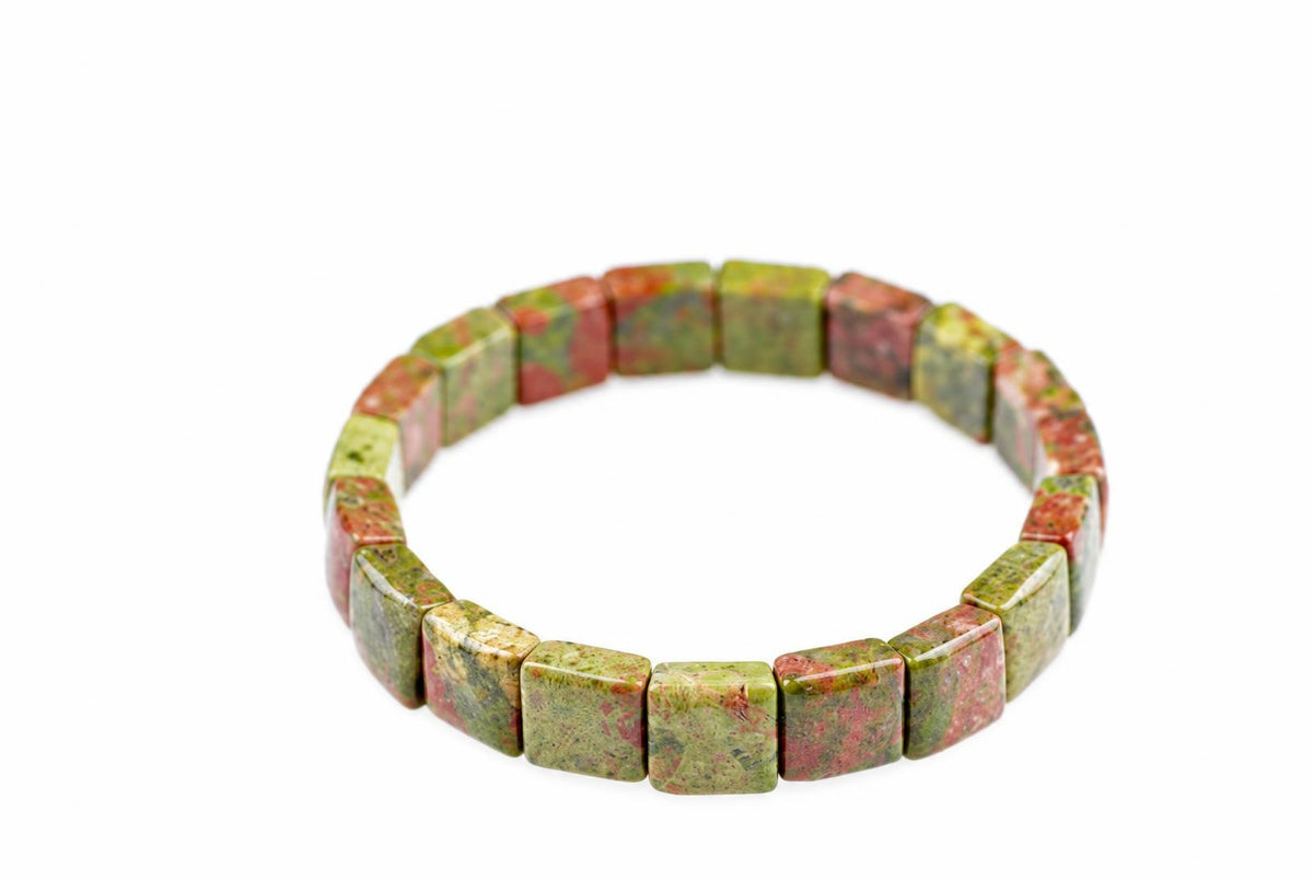 A bracelet made of square beads with green and red speckled patterns, arranged in a circle on a white surface.