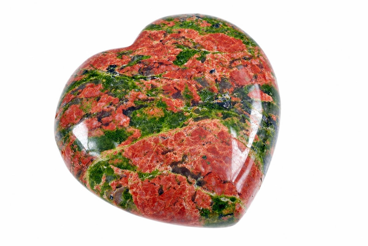 A polished heart-shaped stone with red and green patterns on a white background.