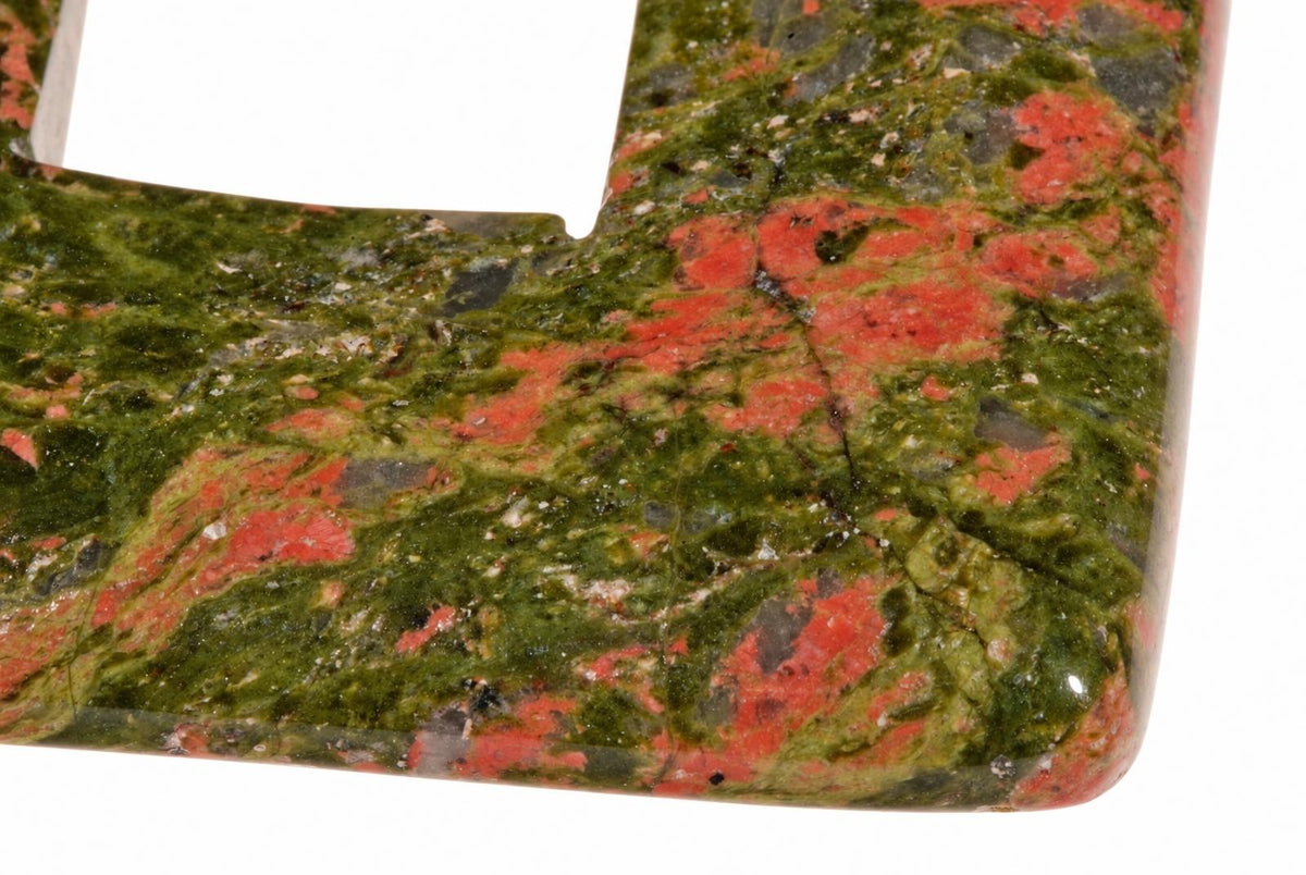 A polished stone pendant with a square shape, featuring green and red speckled patterns on a white background.