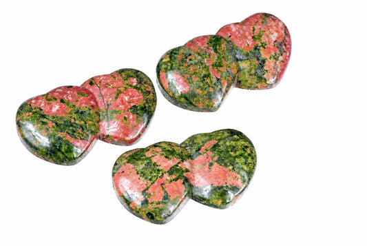 Three polished heart-shaped stones with pink and green patterns on a white background.