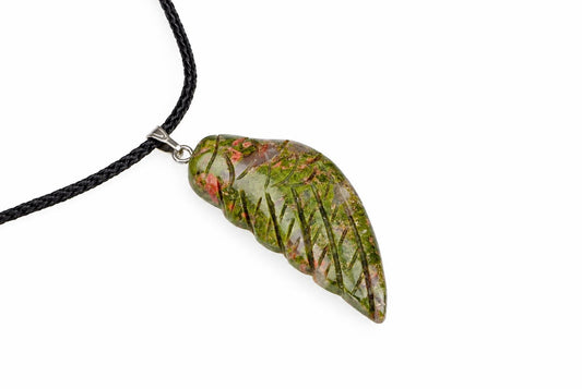 A polished unakite pendant shaped like a wing, featuring green and pink inclusions with dark needle-like crystals, hanging from a black cord on a white surface.