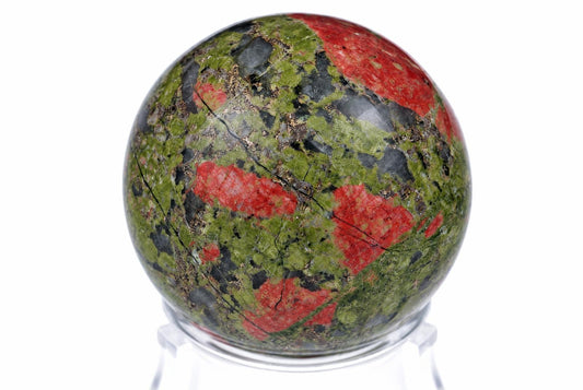 A polished sphere of unakite with green, red and dark patches sits on a clear stand against a white background.