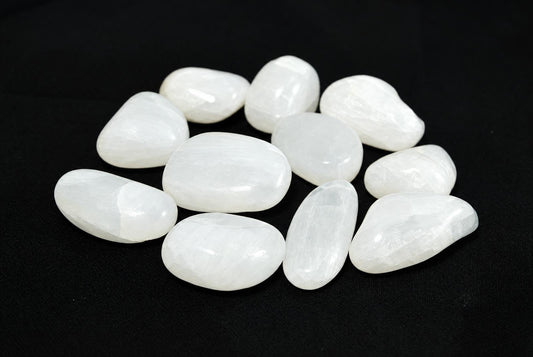 A group of smooth, white stones with a polished surface arranged on a dark background.