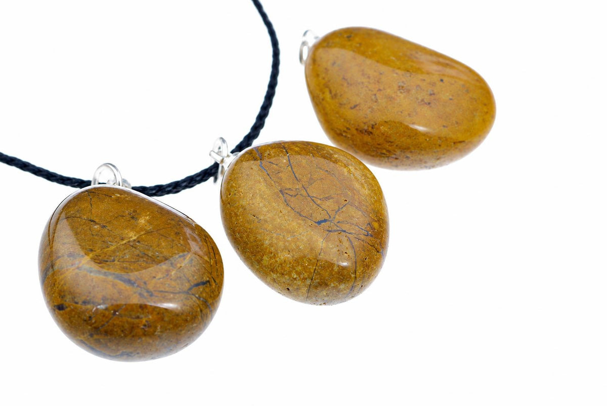 Three polished yellow jasper pebble pendants with silver-toned settings hang from a dark cord against a white background.